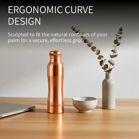 Copper water bottle on a wooden table with text about ergonomic design
