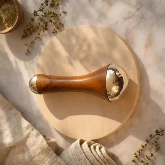 kansa wand on wooden circular board with herbs around 