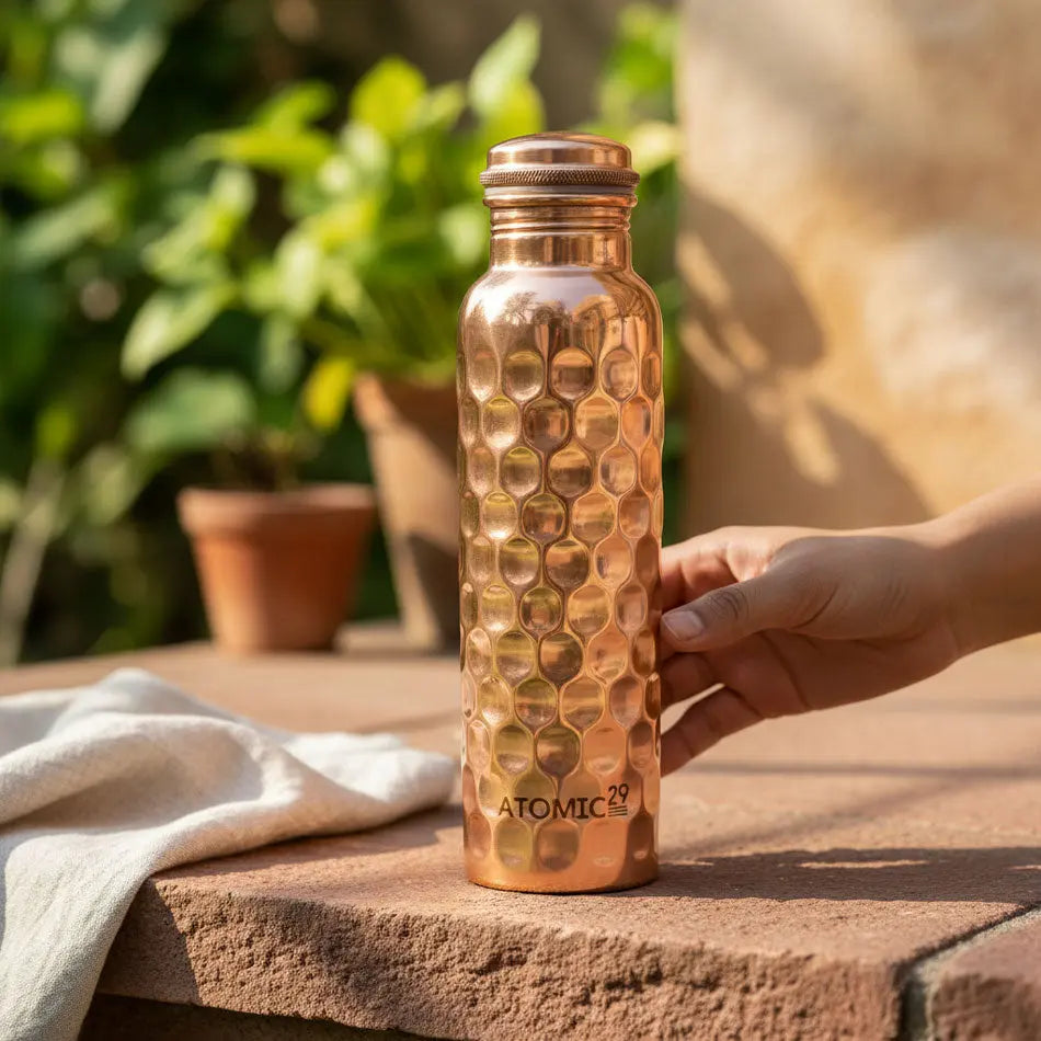diamond honey comb design copper water bottle on a outdoor tile with "Atomic29" branding