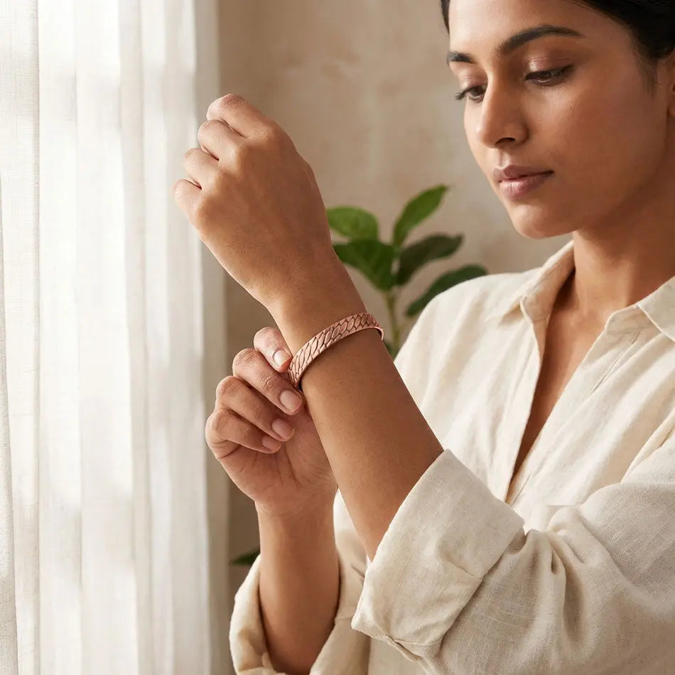 Woman wearing a copper bracelet indoors with a plant in the background