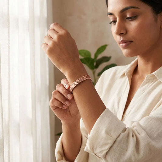 Woman wearing a copper bracelet indoors with a plant in the background