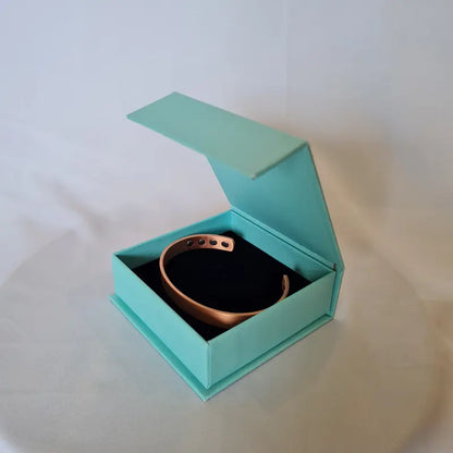 Turquoise bracelet gift box with a black interior containing a copper bracelet on a white background