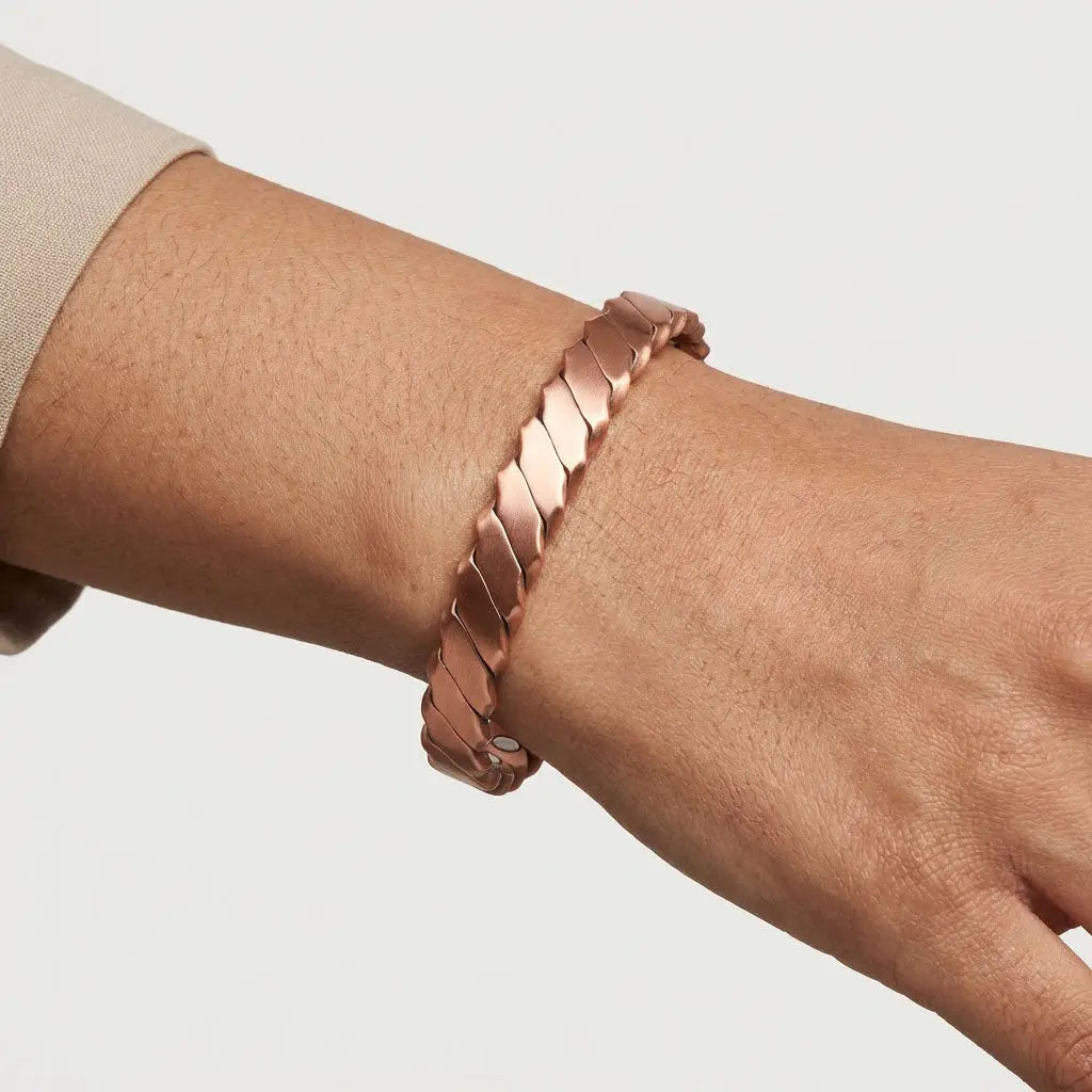 copper bracelet on a wrist against a neutral background
