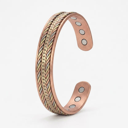 A copper magnetic cuff bracelet with a braided textured pattern and magnetic inserts, shown on a light grey background.