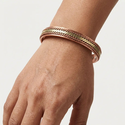 Copper bracelet on a wrist against a light gray background
