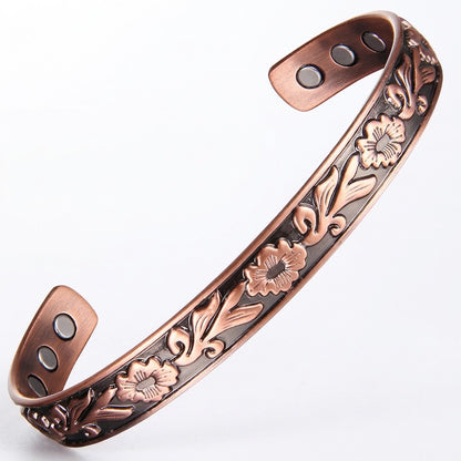 A copper magnetic therapy cuff bracelet with embossed floral patterns and three circular magnets on each end, shown on a plain white background.