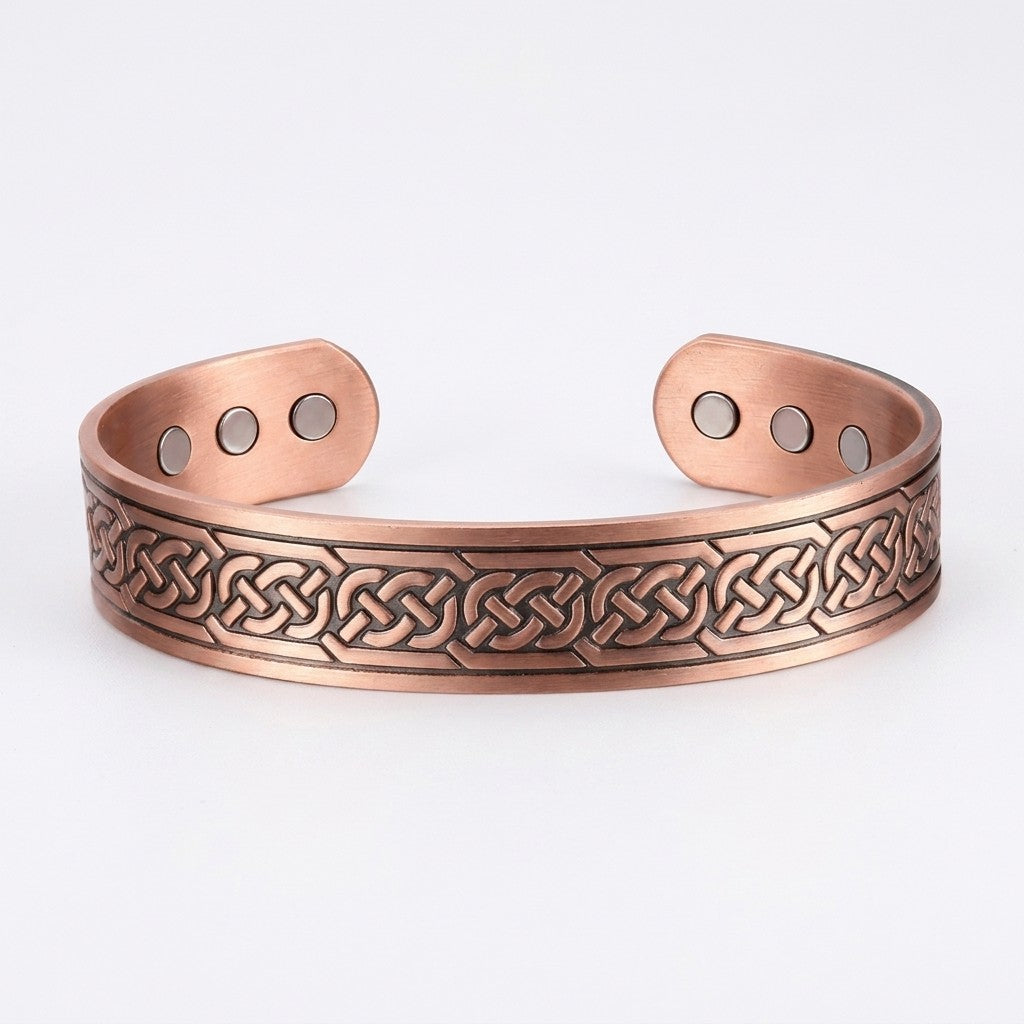 A copper cuff magnetic bracelet featuring an engraved Celtic knot pattern on the front, with three small circular magnets on each end for attachment.