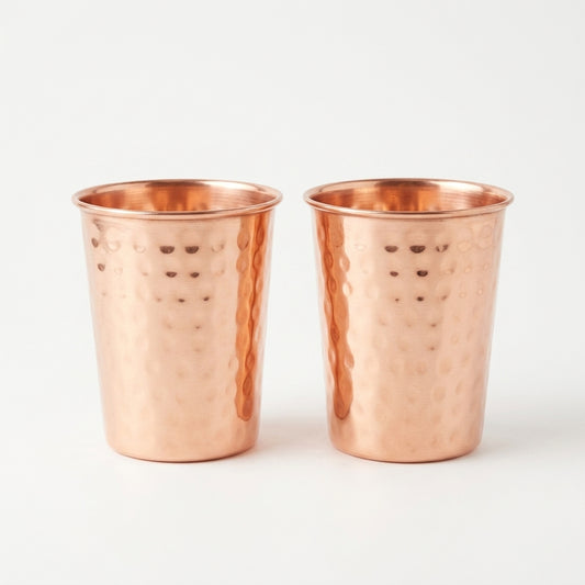 Two copper tumblers with a hammered texture on a white background