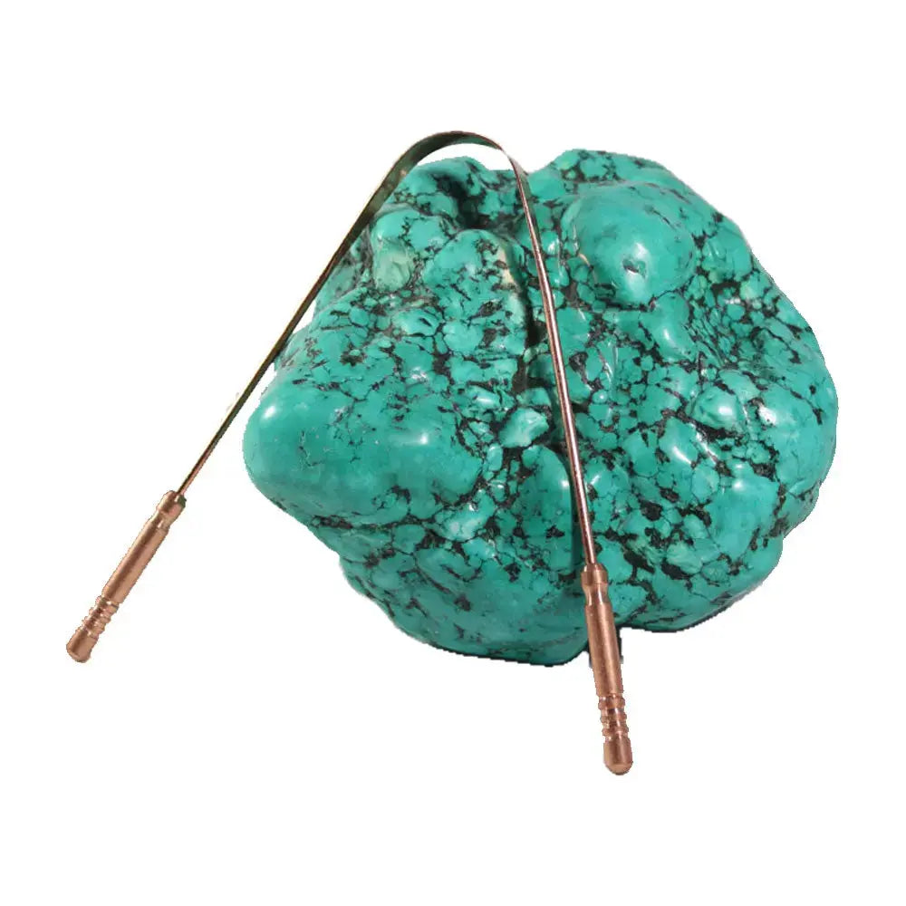 Turquoise stone with a copper tongue scrapper on a white background