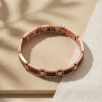 A copper magnetic therapy link bracelet with carbon fibre rectangular inlays, displayed on a textured beige surface.