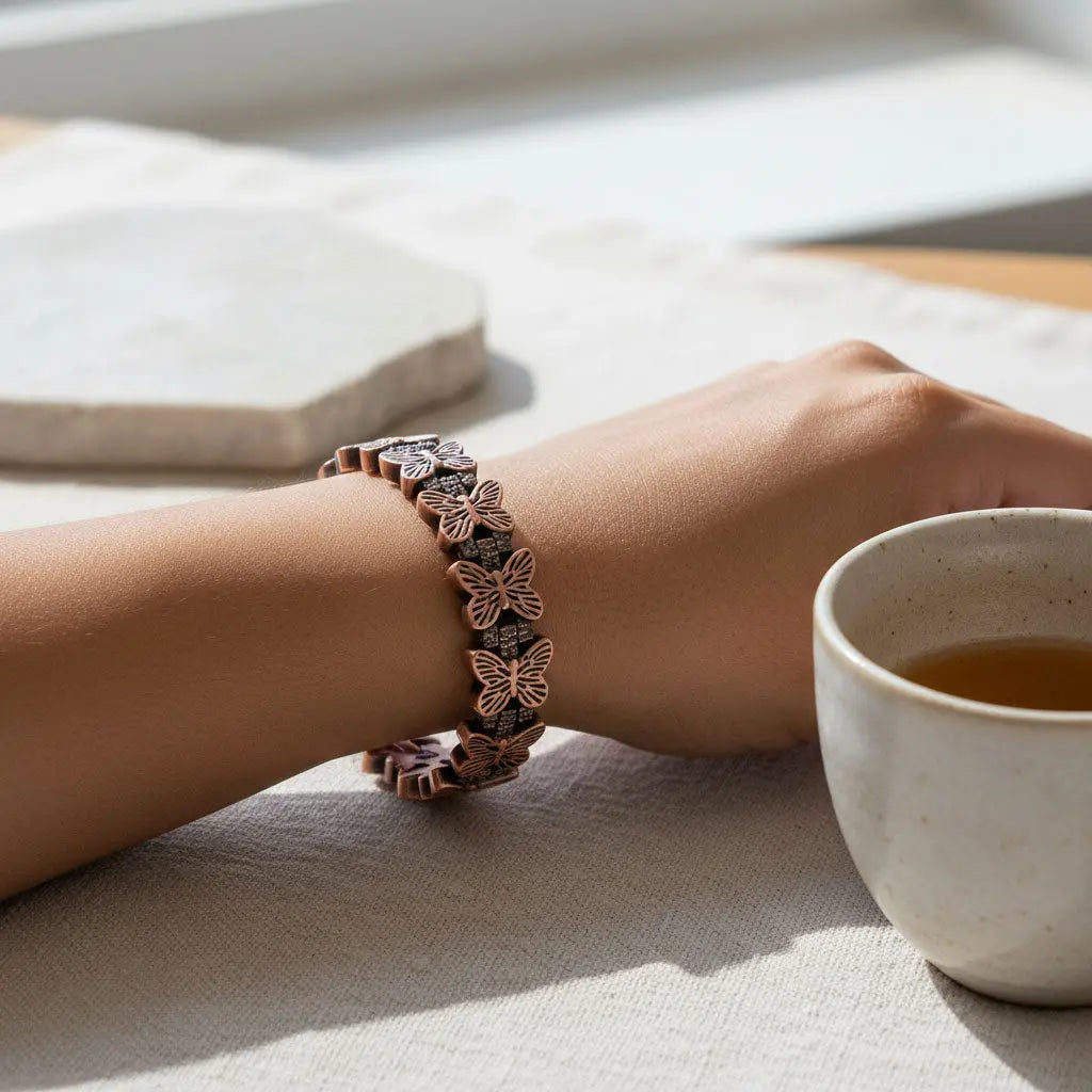 Butterfly-patterned bracelet on a wrist with a cup of tea in the background