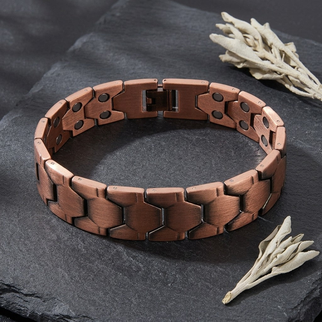 A copper magnetic bracelet HEXA flexi range displayed on a dark slate surface with dried white flowers as props.