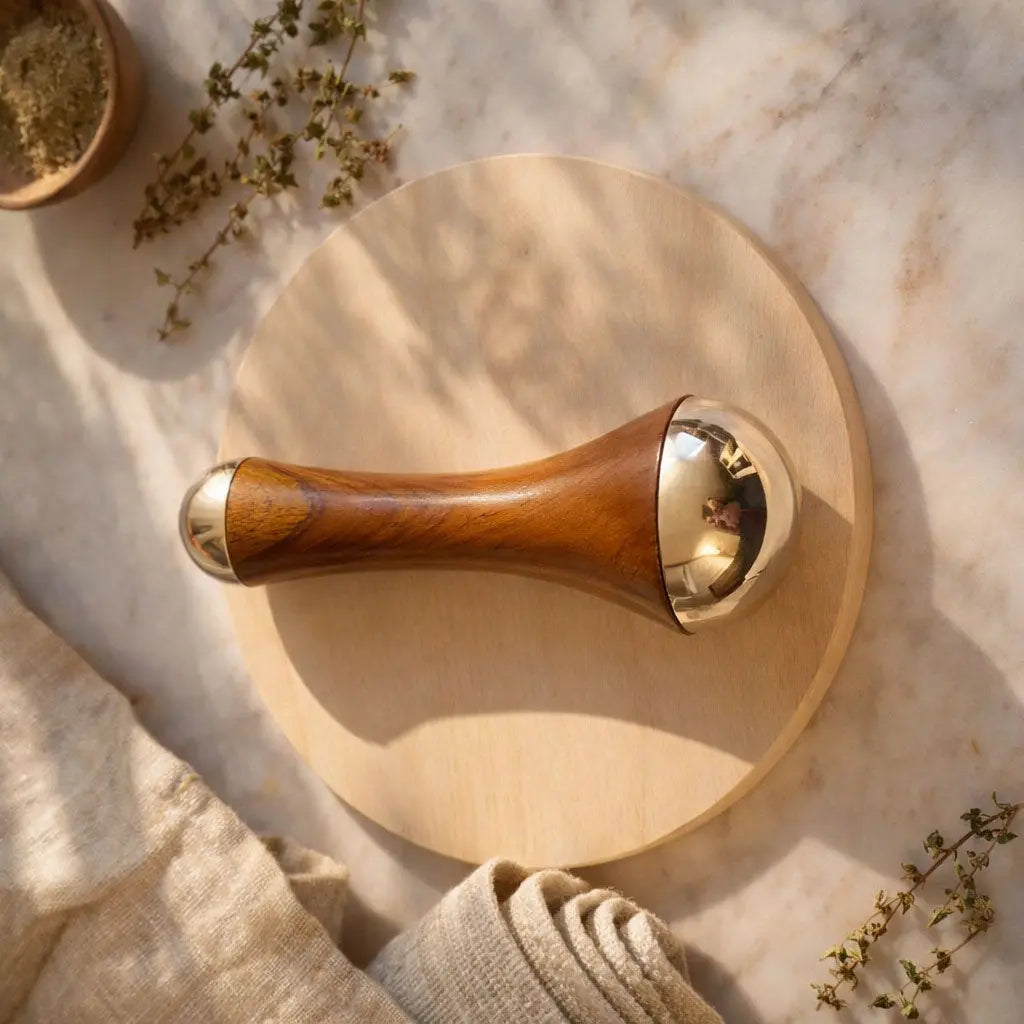 kansa massage wand on a marble surface with herbs and a cloth