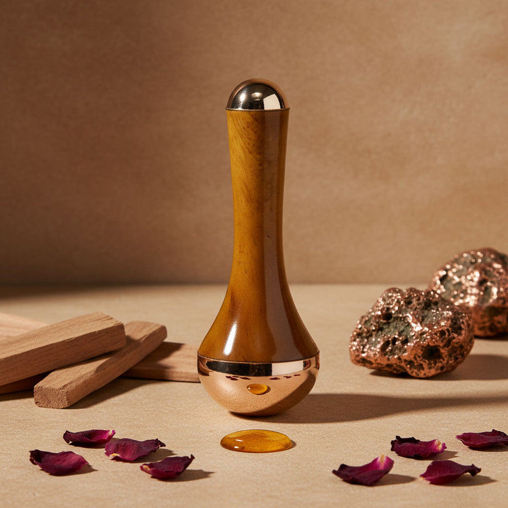 Kansa massage tool with rose petal, honey drop and copper rocks around it