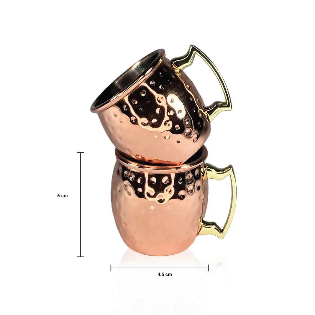 Two stacked copper shot mugs with gold handles on a white background