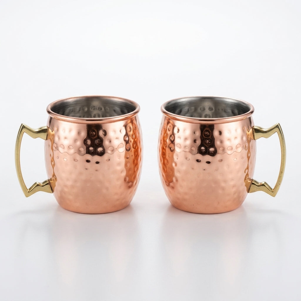 Two copper mugs with gold handles on a white background