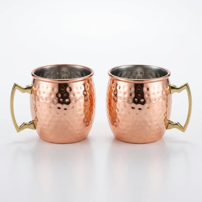Two copper mugs with gold handles on a white background