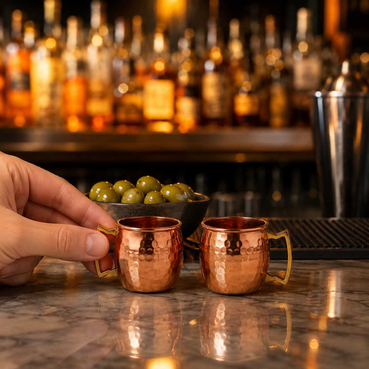 mini shot glasses on a bar table with a hand holding it
