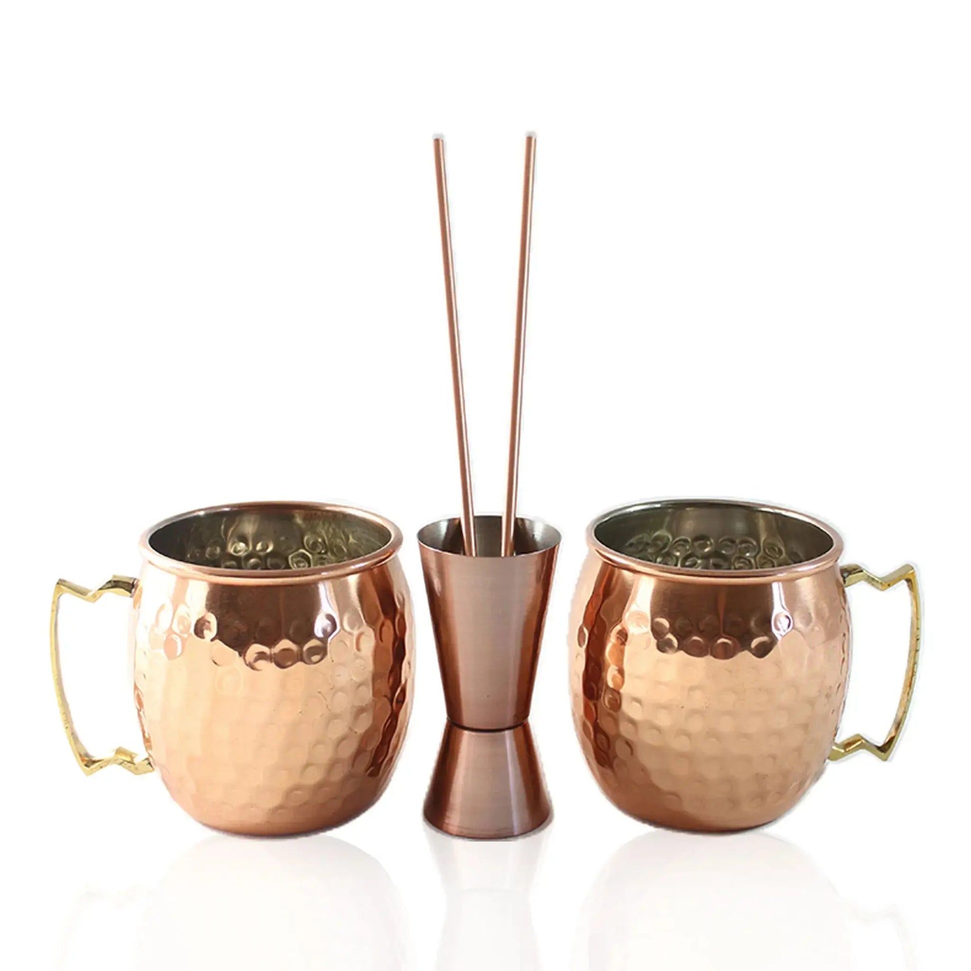 Set of two copper mugs, straws and a jigger on a white background