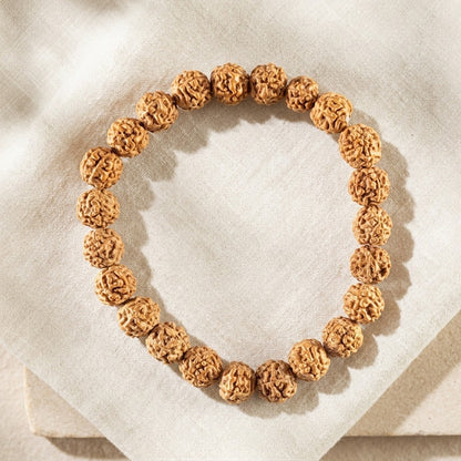 A rudraksha beaded bracelet, on a light beige linen fabric background.