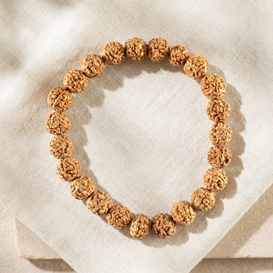 A rudraksha beaded bracelet, on a light beige linen fabric background.