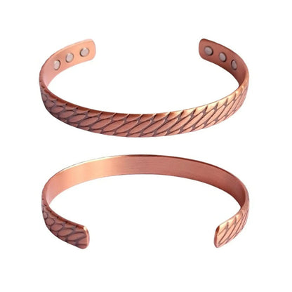 Two copper bracelets with embossed design on a white background