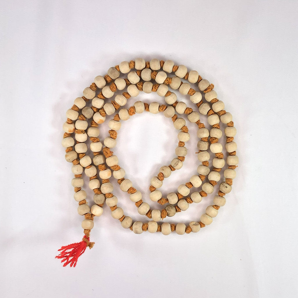 Meditation mala with tulsi (holy basil) beads and a red tassel on a white background