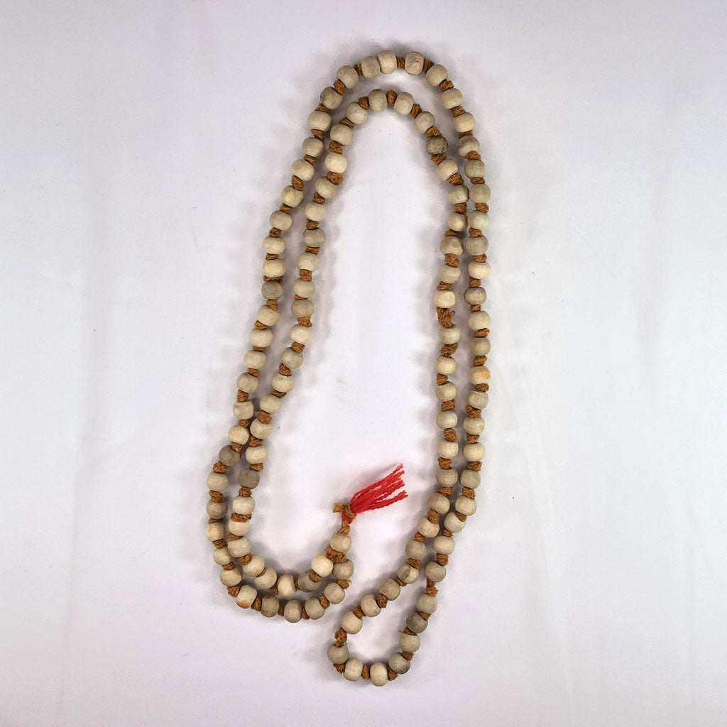 Long string of tulsi (Holy Basil) 108 beads with a red tassel on a white background