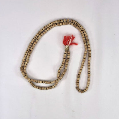 String of tulsi (holy basil) beads with a red tassel on a white background