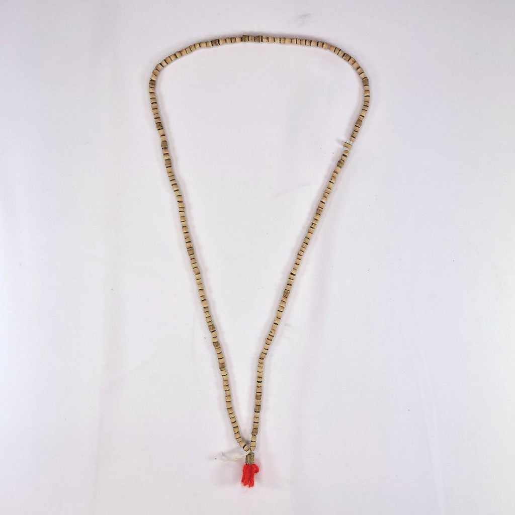 Necklace with tulsi (holy basil) beads and a red tassel on a white background